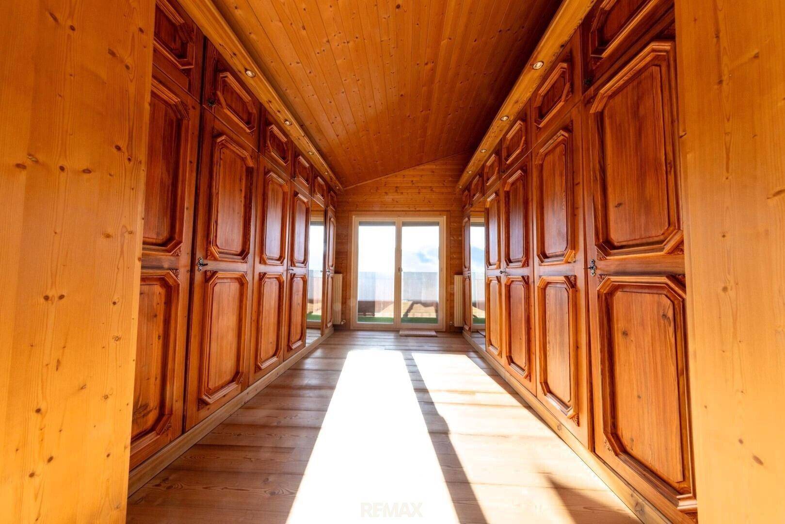 Geräumiger begehbarer Kleiderschrank mit maßgefertigten Holzschränken und viel natürlichem Licht.