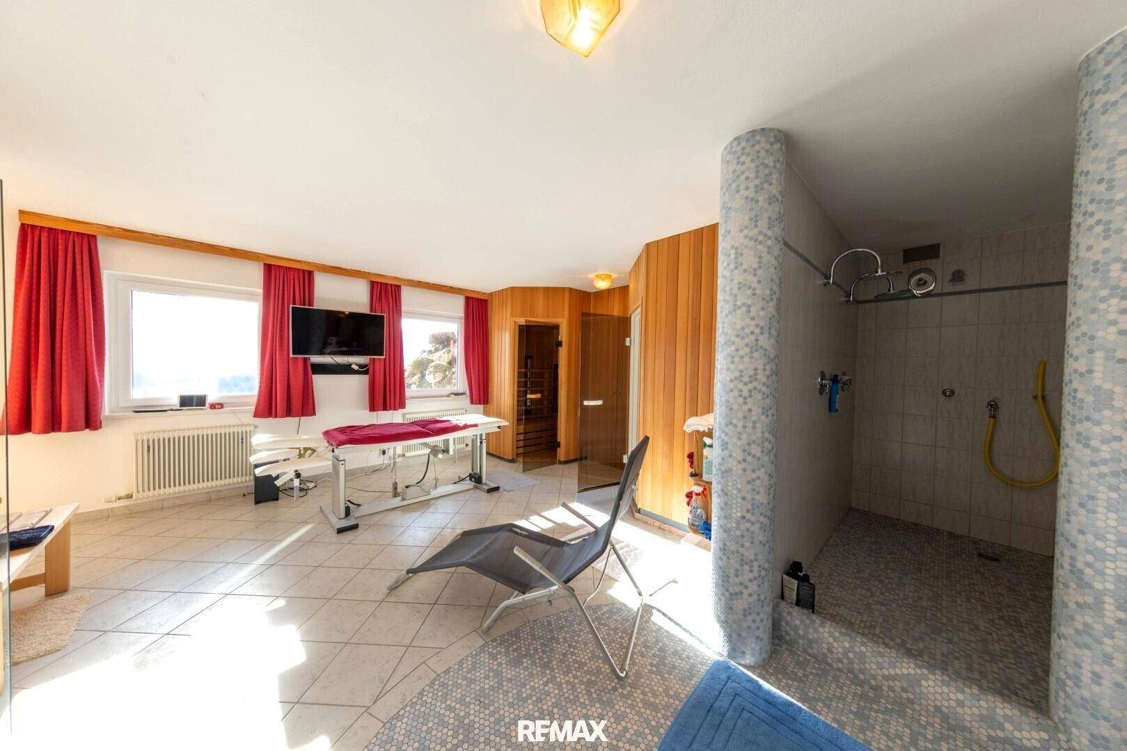 Wellnessbereich mit Mosaikdusche, Holzsaunen und einem Entspannungsbereich mit viel Tageslicht.
