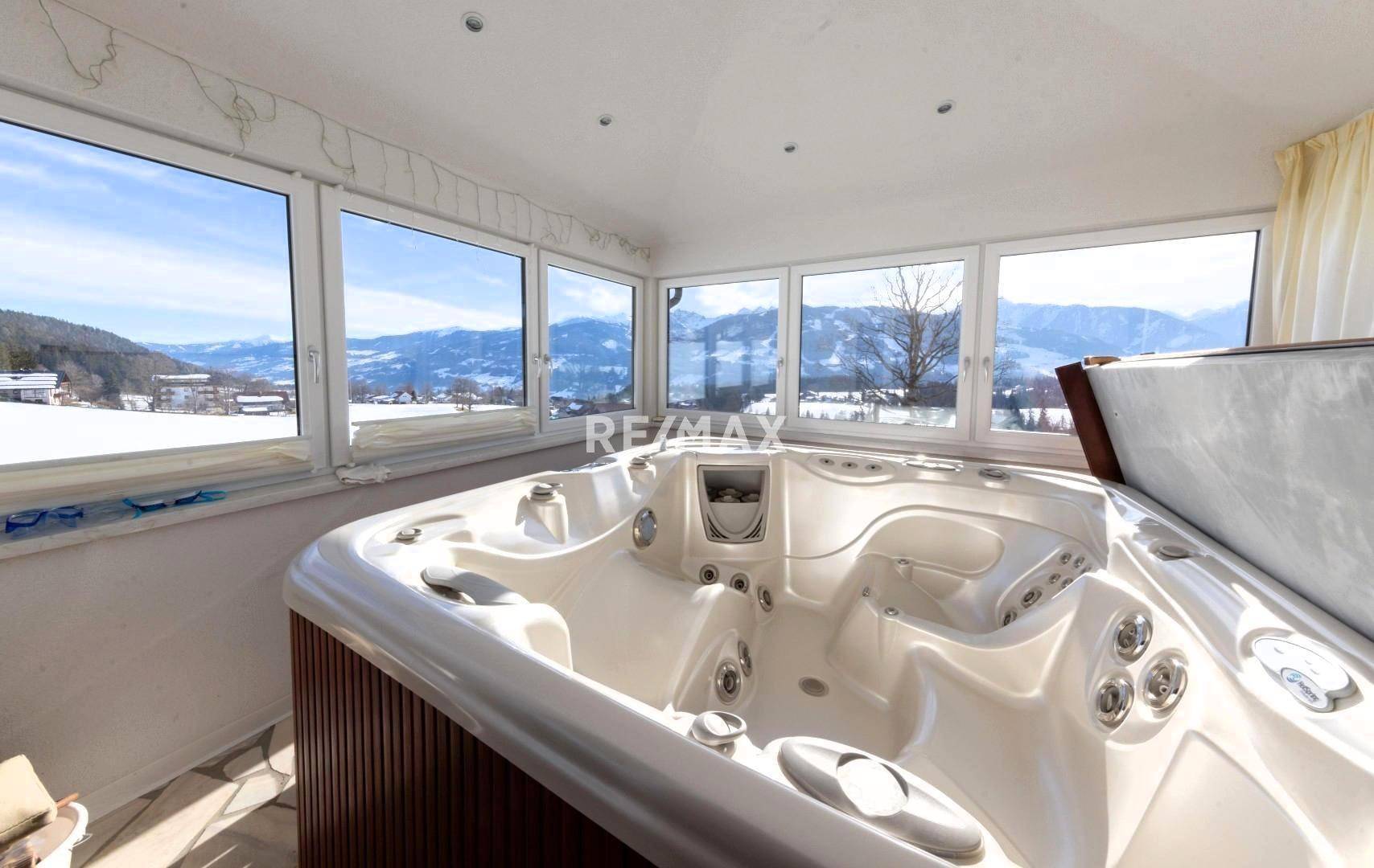 Gemütlicher Wintergarten mit Whirlpool und großen Fenstern, bietet entspannenden Bergblick.