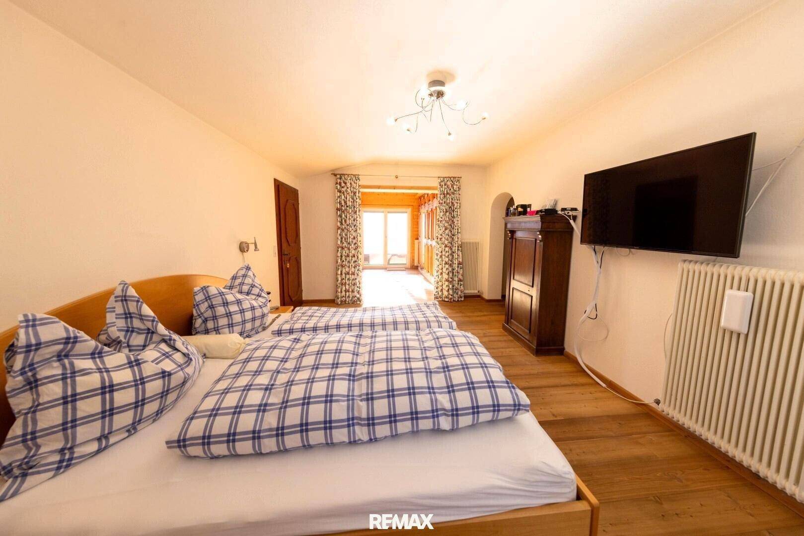 Gemütliches Schlafzimmer mit zwei Einzelbetten, Holzboden und einem Heizkörper unter dem Fenster.