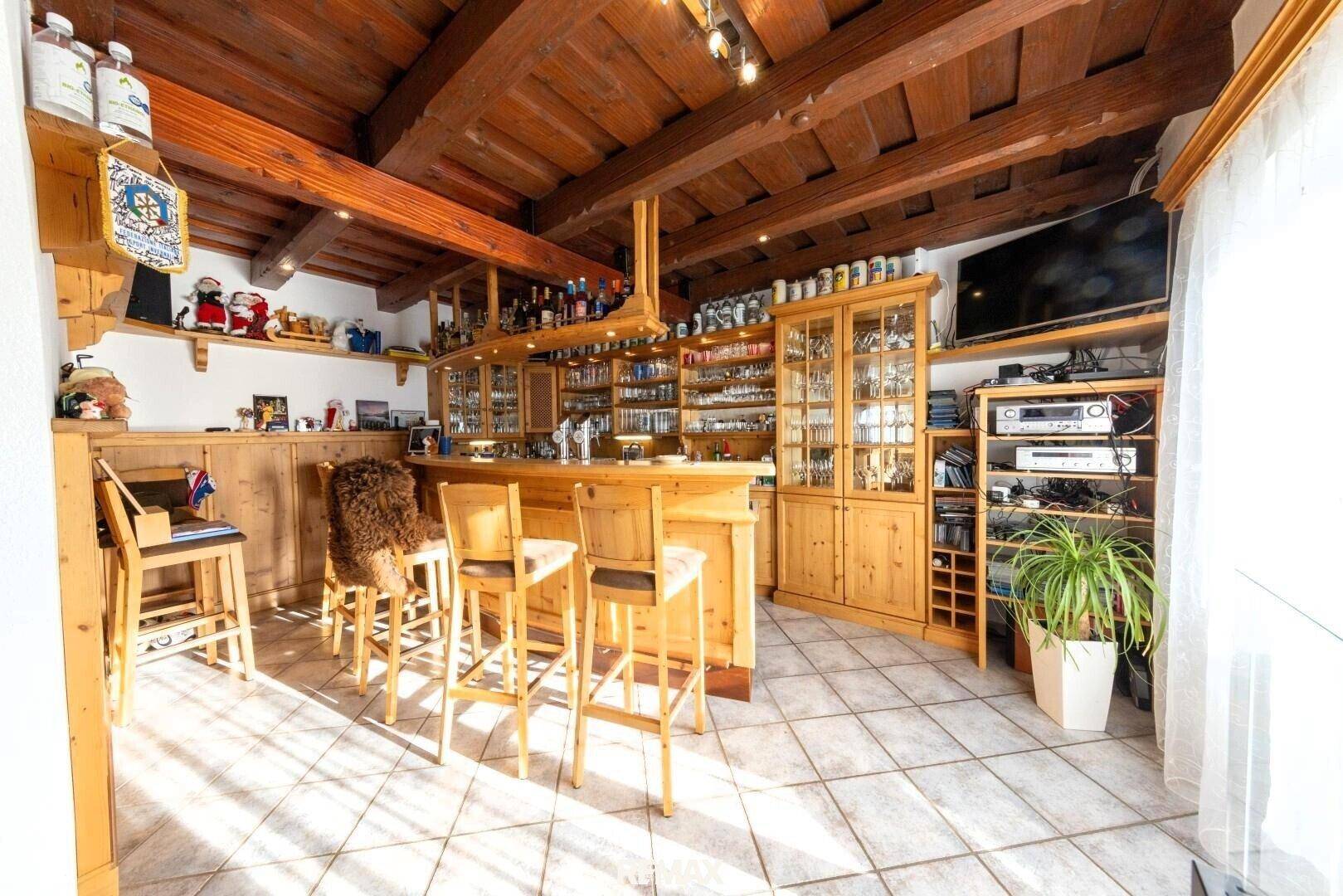 Rustikale Hausbar mit Holzeinrichtung, Barhockern und reichlich Stauraum für Gläser und Flaschen.