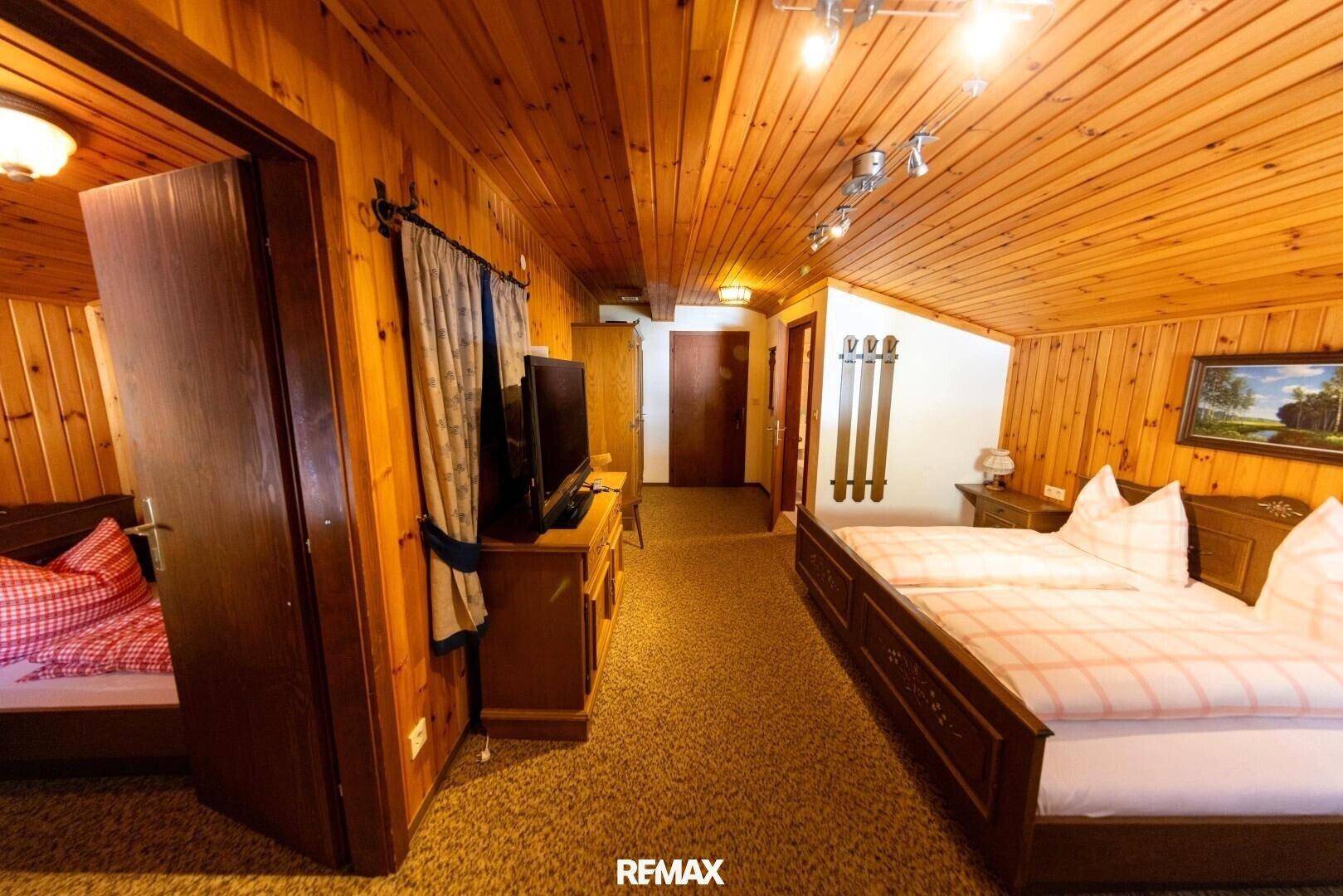 Gemütliches Schlafzimmer im alpinen Stil mit Holzvertäfelung, Teppichboden und traditionellen Möbeln.