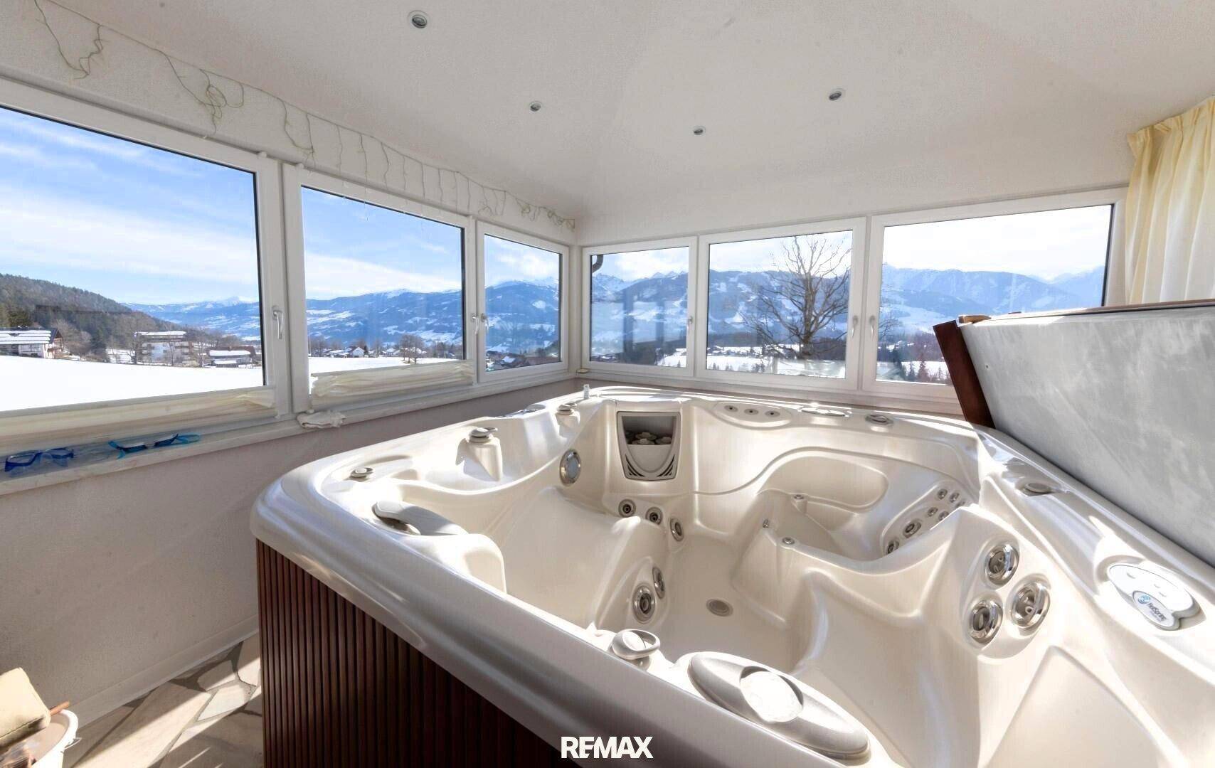 Raum mit großem Whirlpool und Panoramafenstern, die einen atemberaubenden Blick auf die Berge bieten.