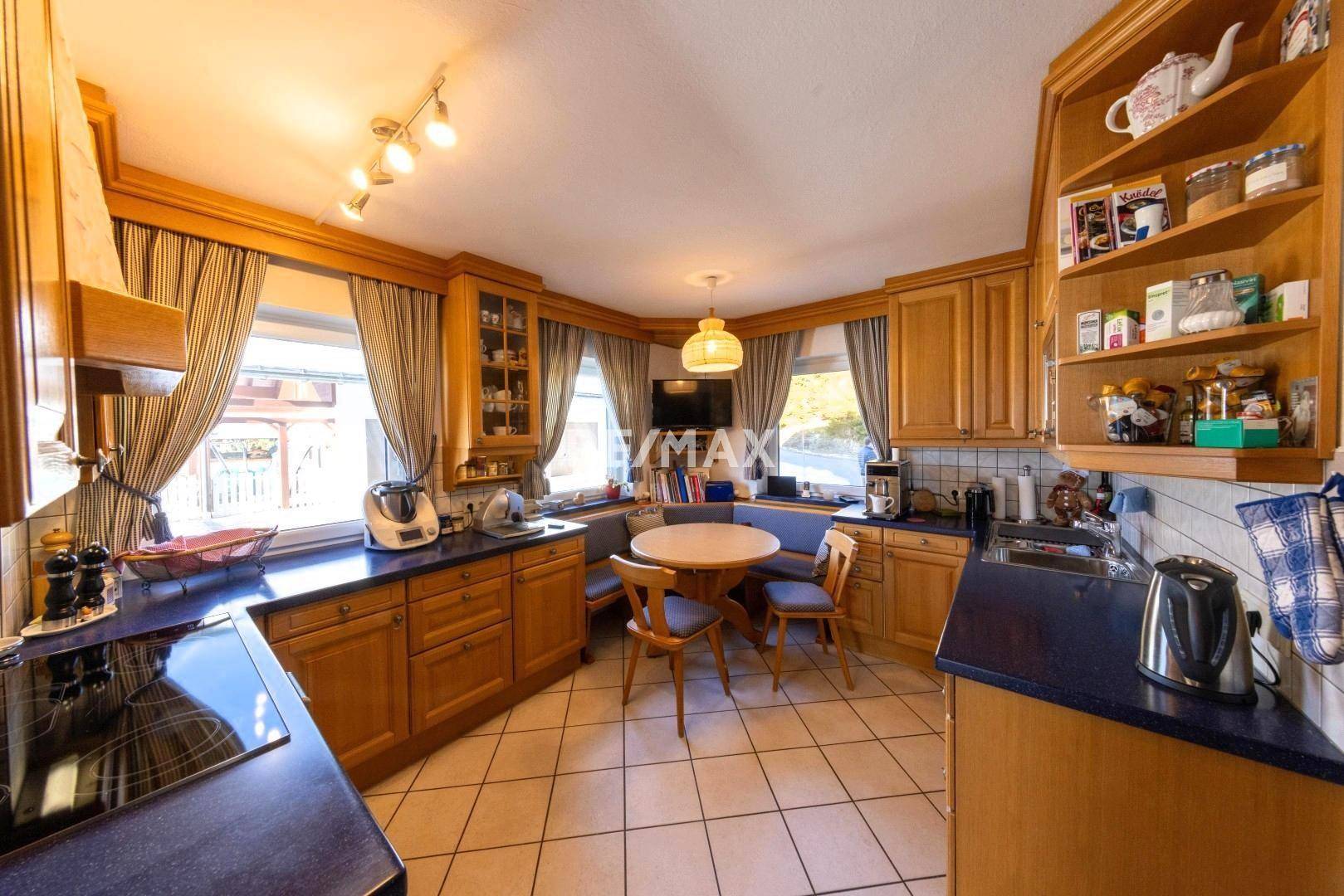 Traditionelle Holzküche mit blauen Arbeitsplatten, Essecke und gefliestem Boden, gut ausgestattet.