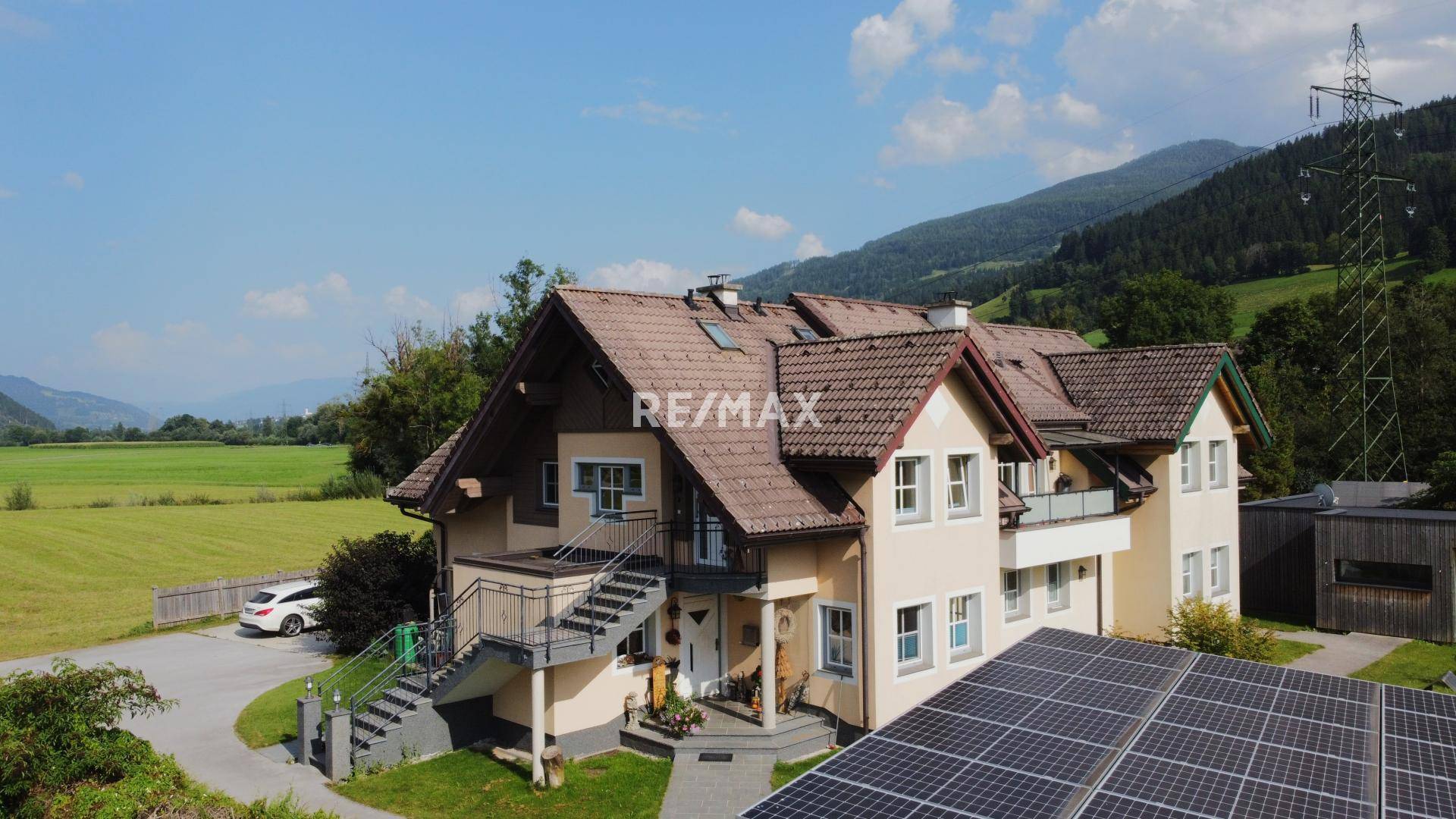 Luftaufnahme des Anwesens mit Solaranlage, umgeben von grünen Feldern und Bergen.