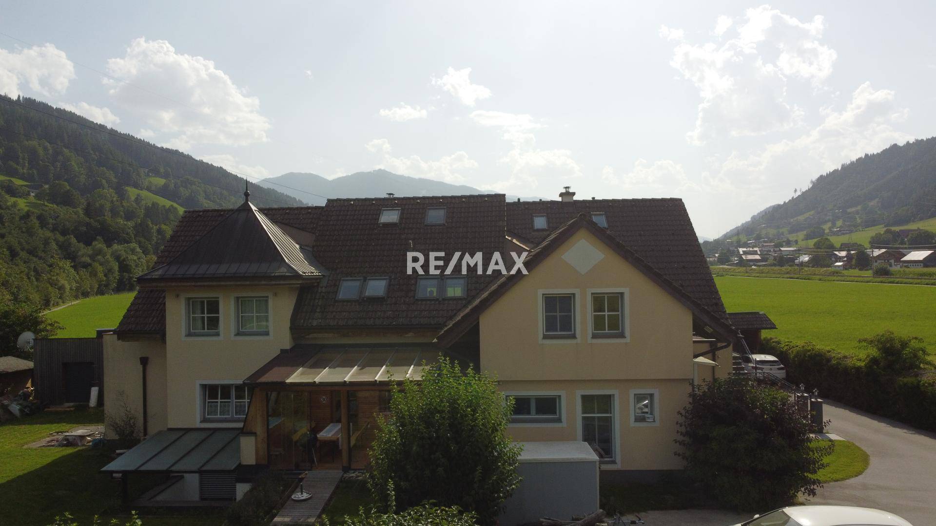 Vogelperspektive des Hauses mit Wintergarten und mehreren Dachfenstern in ländlicher Umgebung.