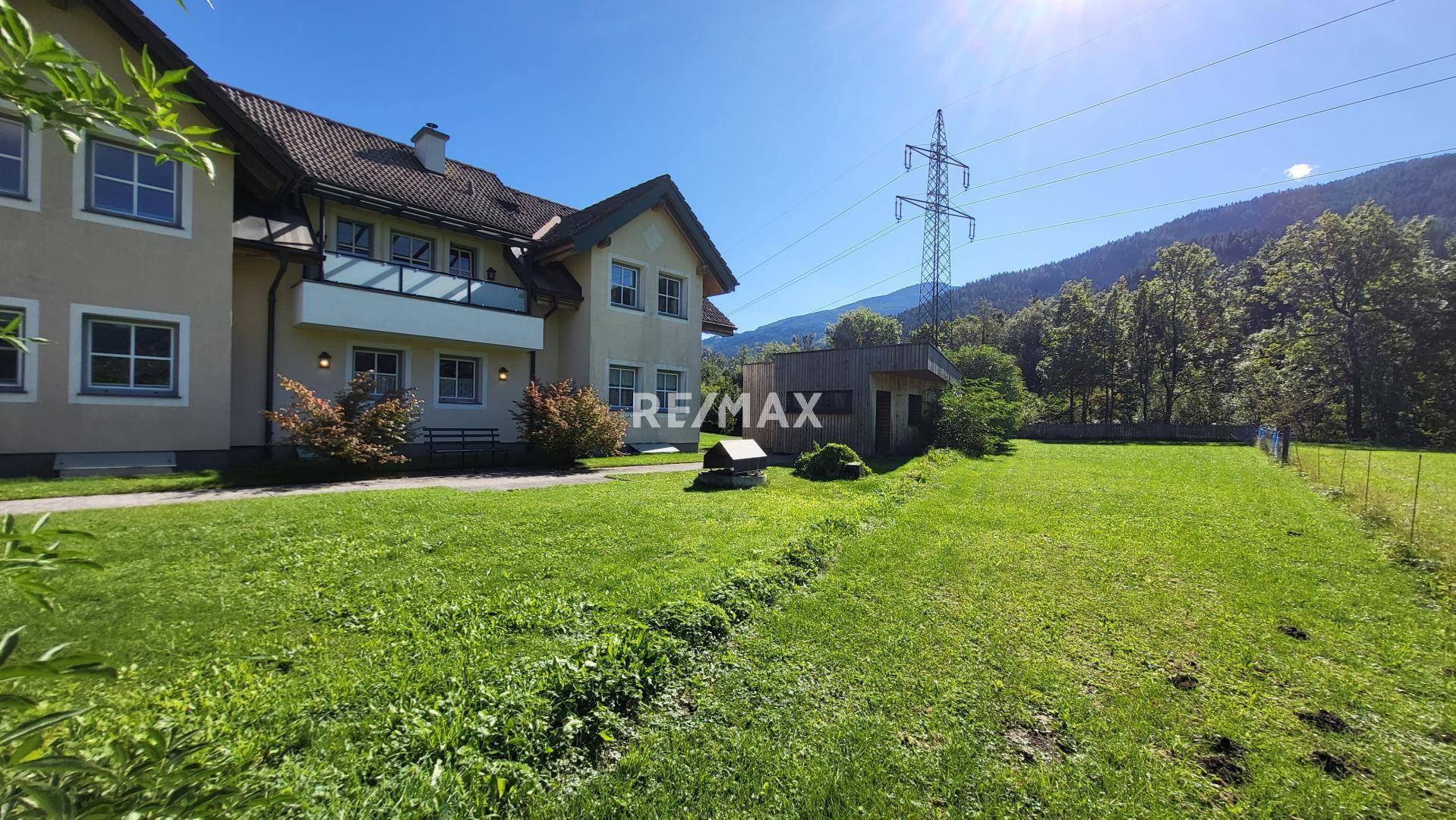 Seitlicher Blick auf das Haus mit weitläufigem Rasenbereich und angrenzendem Zaun.