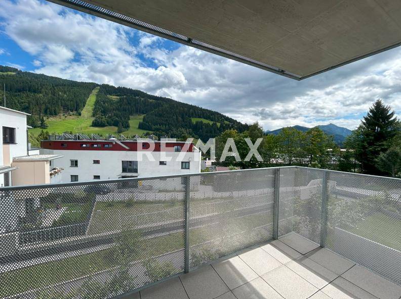 Geräumiger Balkon mit Fliesenboden und weitem Blick auf die umliegenden Berge und grüne Hänge.