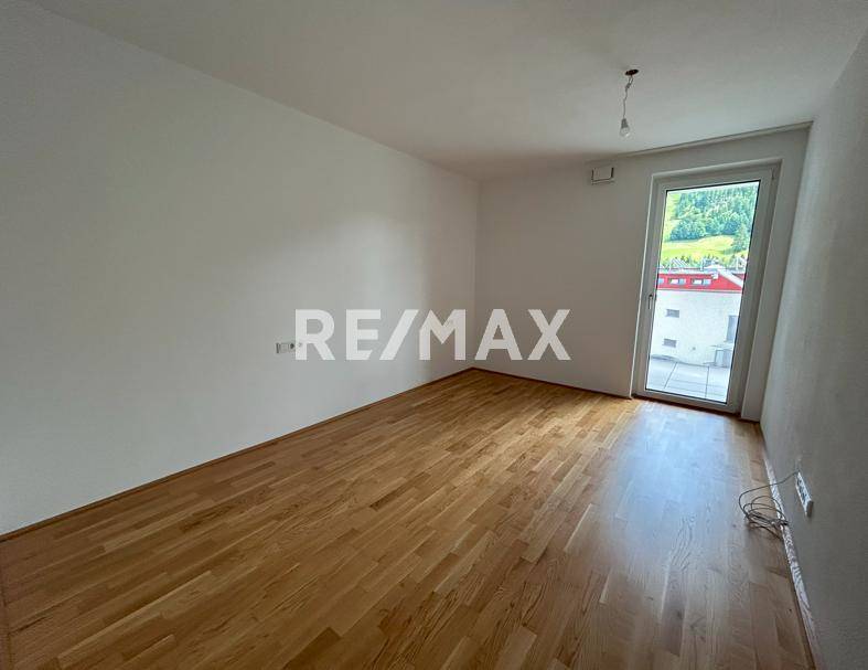 Helles Schlafzimmer mit Parkettboden und Zugang zu einem Balkon mit Bergblick.