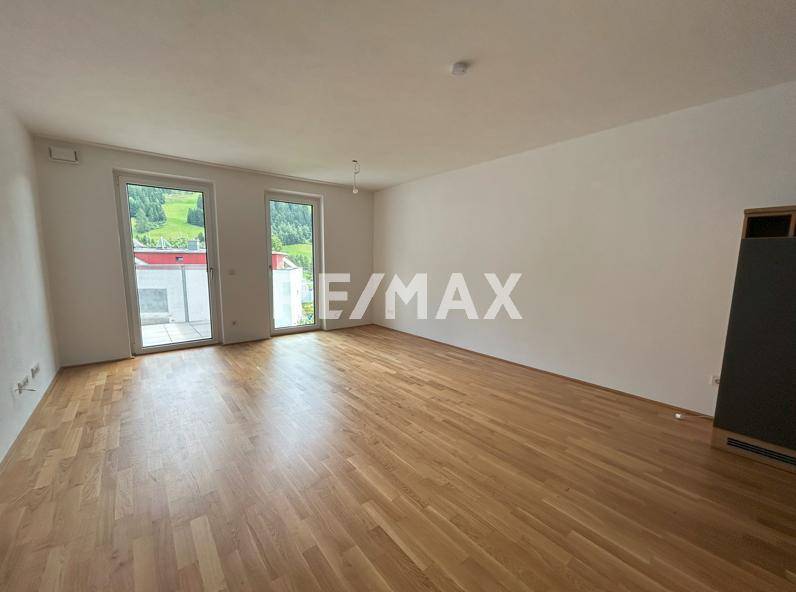 Heller Wohnraum mit Parkettboden und Zugang zu einem Balkon mit Bergblick.