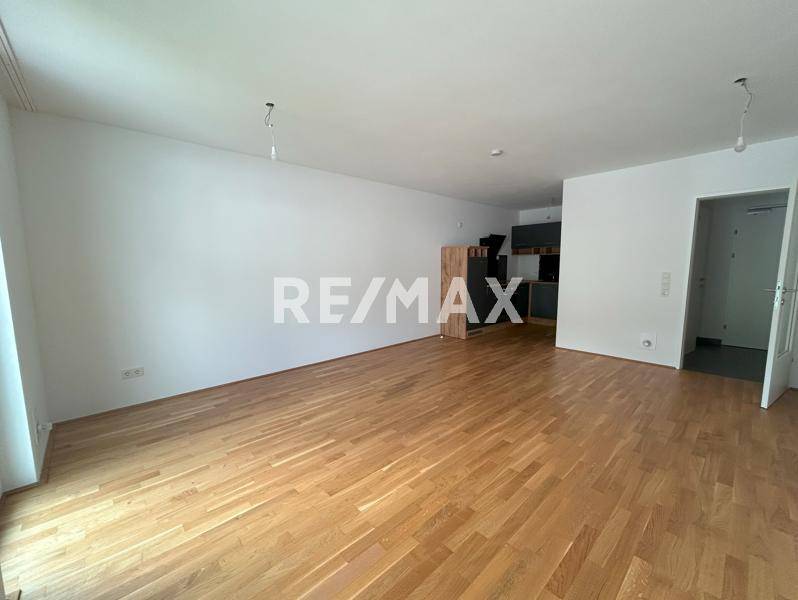 Geräumiger Wohnbereich mit Holzboden, der in einen Küchenbereich übergeht und viel Platz bietet.