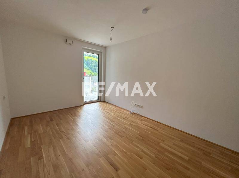 Geräumiges Zimmer mit Holzboden und Fenster, das viel Tageslicht hereinlässt.