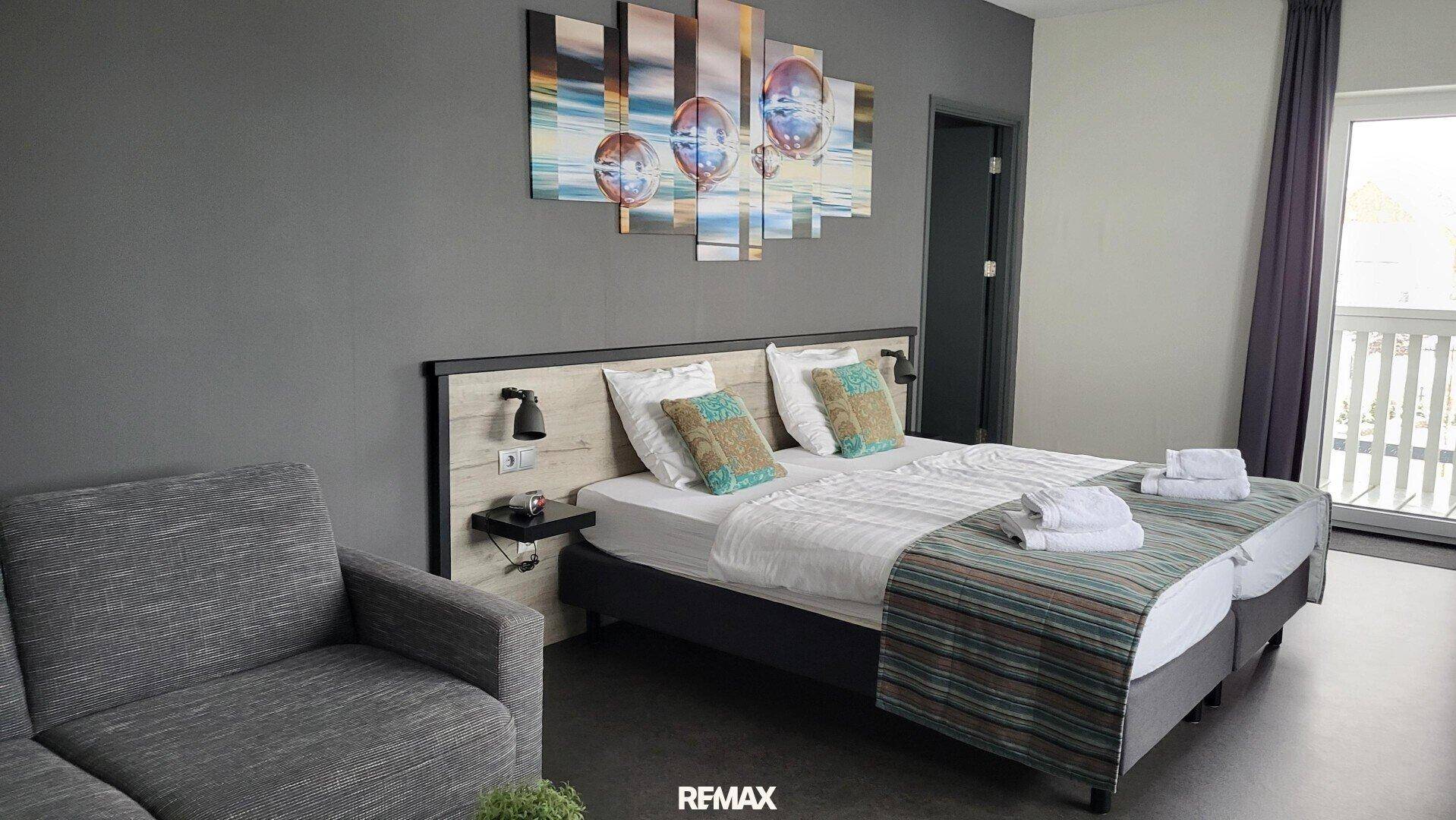 Komfortables Schlafzimmer mit Doppelbett, Sofa und moderner Wanddekoration.