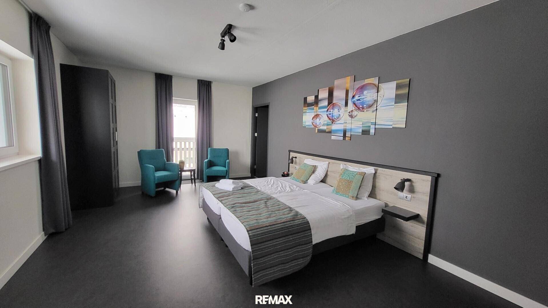 Modernes Schlafzimmer mit Doppelbett, dunklem Boden und farbenfroher Wandkunst.