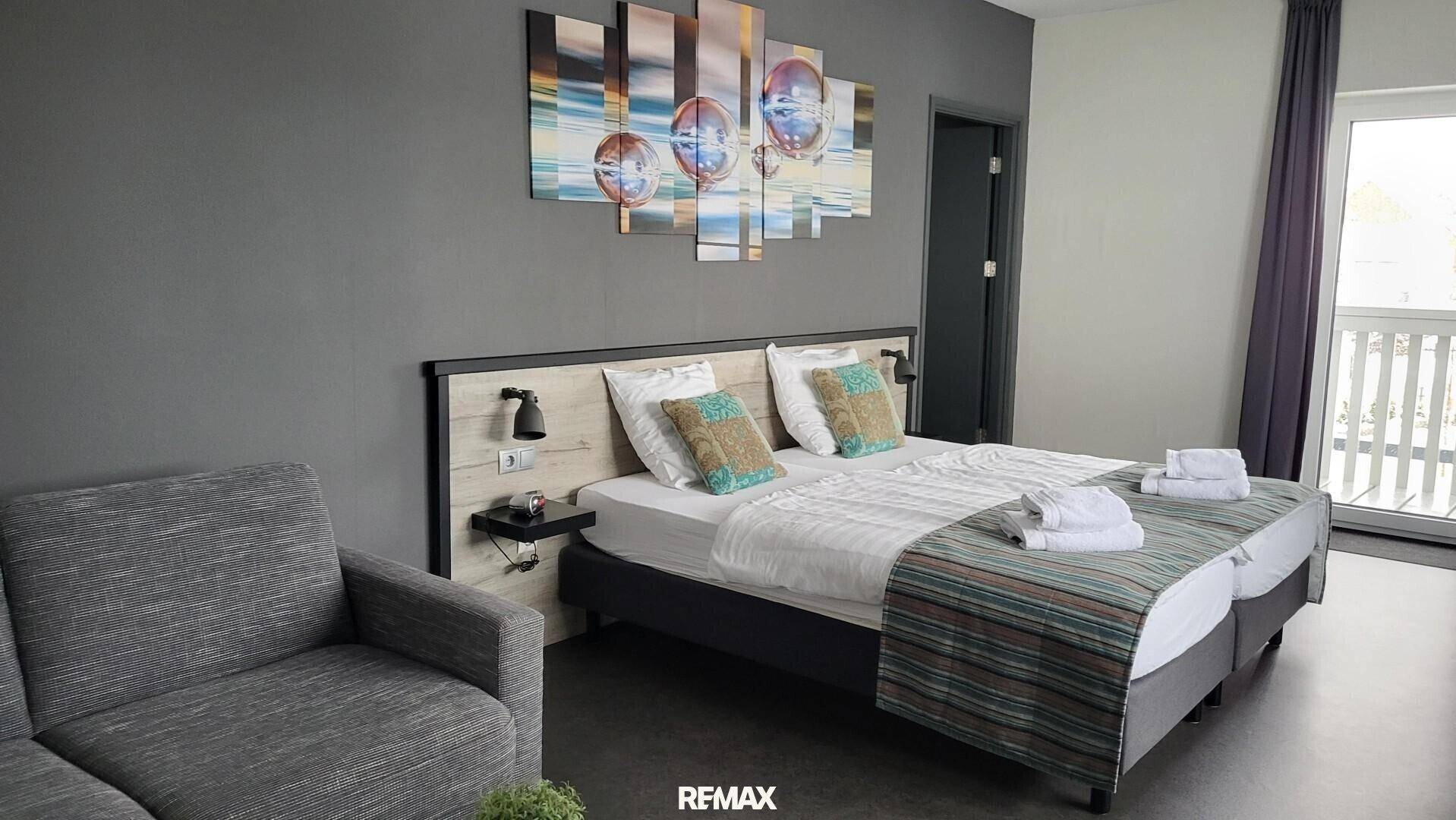 Komfortables Schlafzimmer mit zwei Einzelbetten, einem Sofa und Zugang zum Balkon.