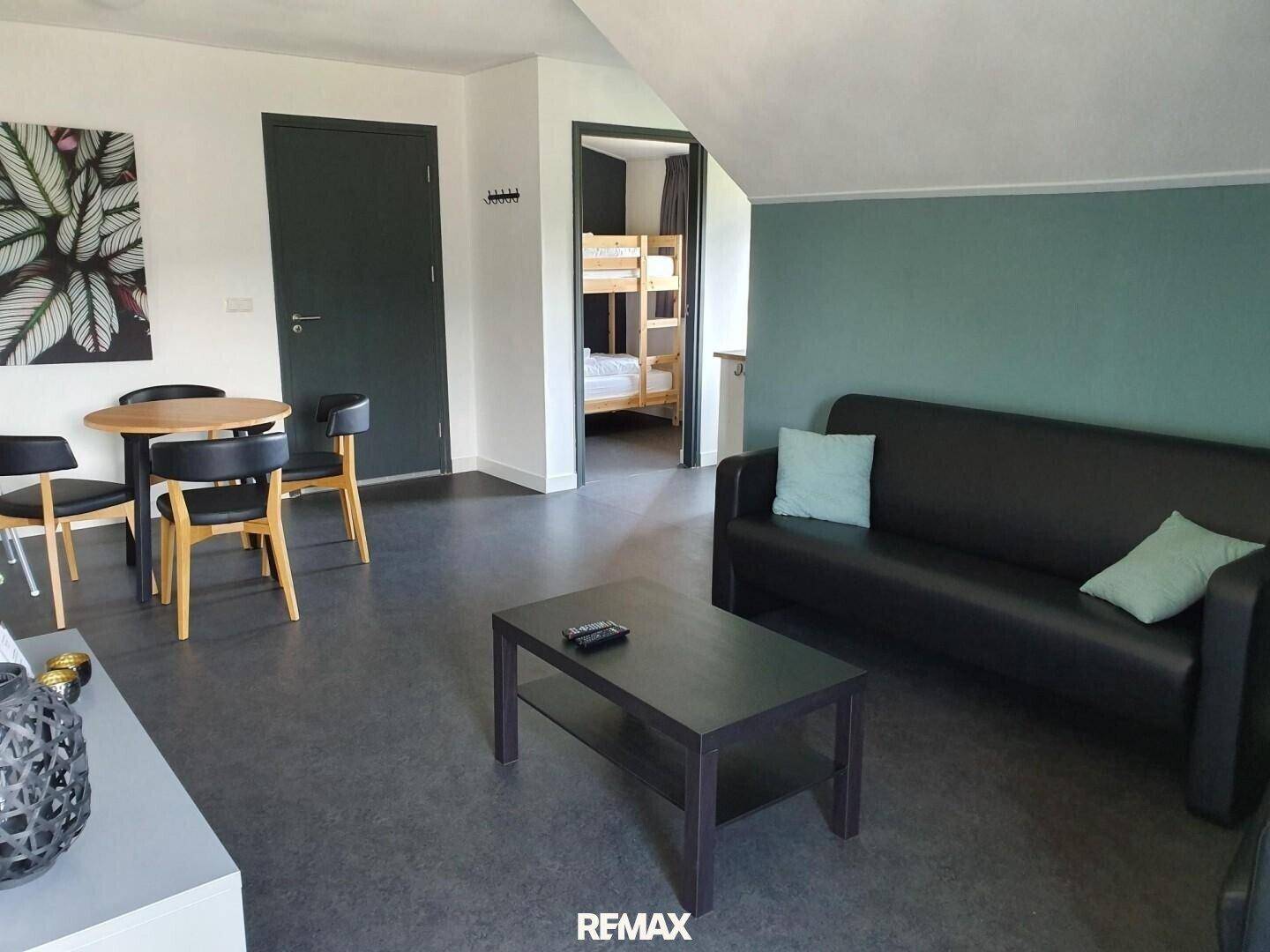 Offener Wohn- und Essbereich mit Sofa, Esstisch und Zugang zu einem weiteren Zimmer.