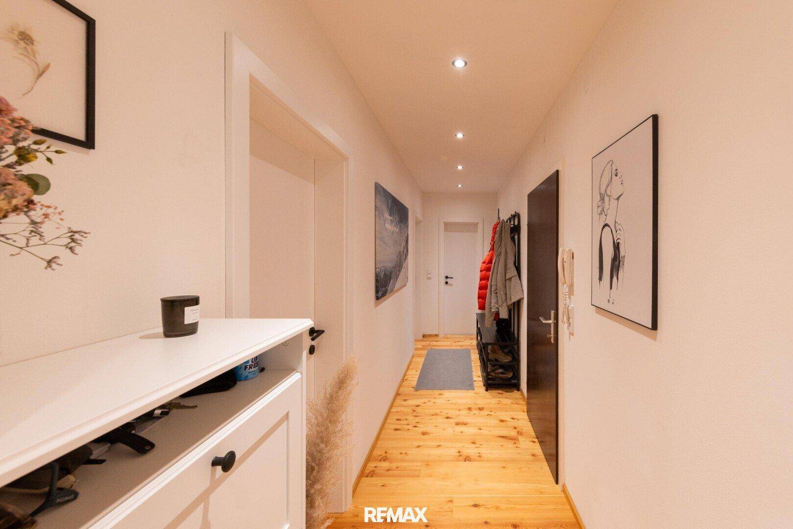 Heller Flur mit Holzboden, Garderobe und Schuhschrank.