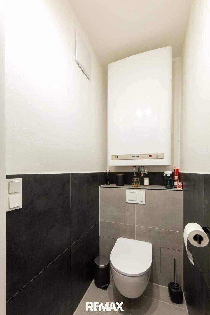 Modernes Gäste-WC mit Wand-WC und dunklen Fliesen.