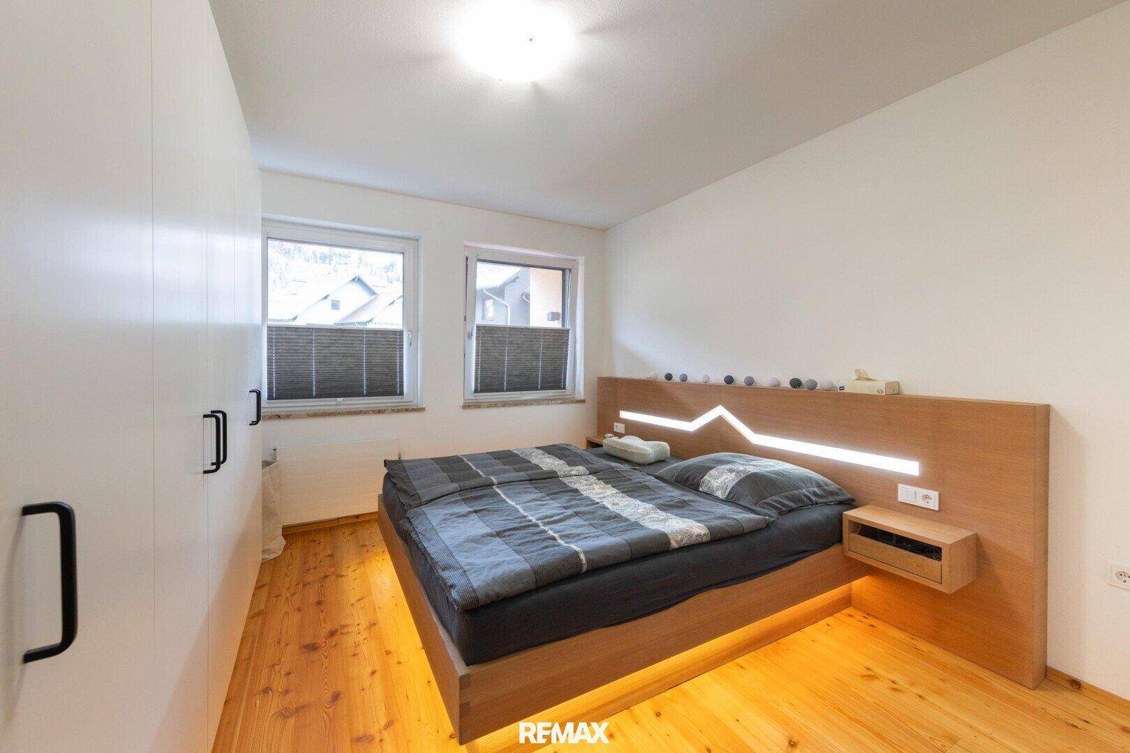 Schlafzimmer mit Holzbett, integrierter Beleuchtung und Holzboden.