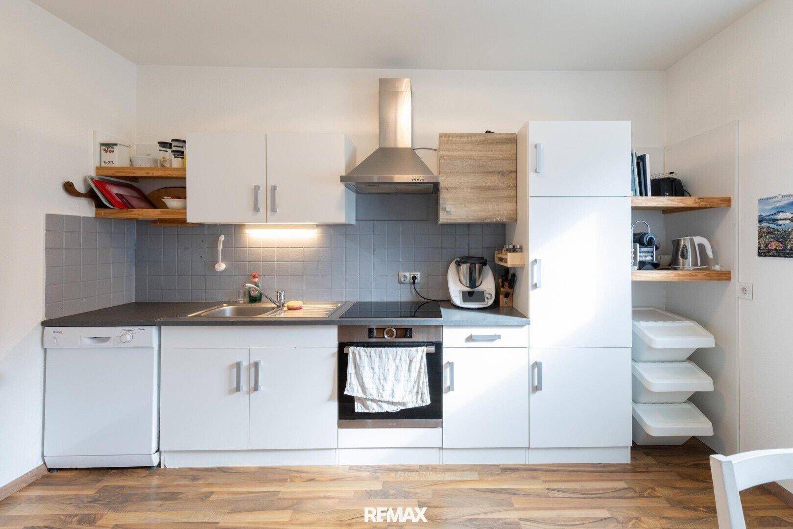 Moderne Einbauküche mit weißen Schränken, Spülmaschine und Kochfeld.