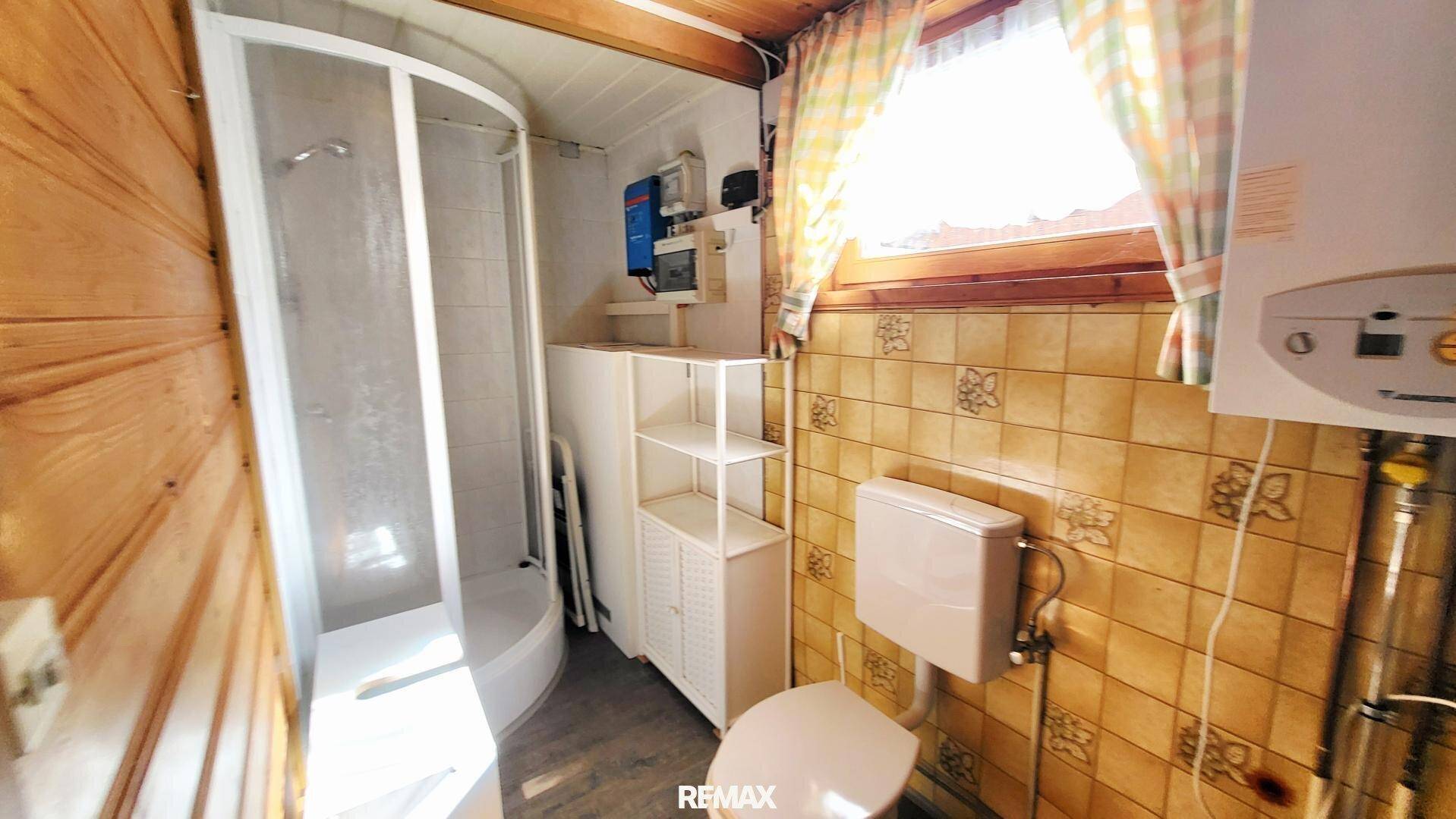 Kleines Badezimmer mit Duschkabine, WC und traditionellen Fliesen.