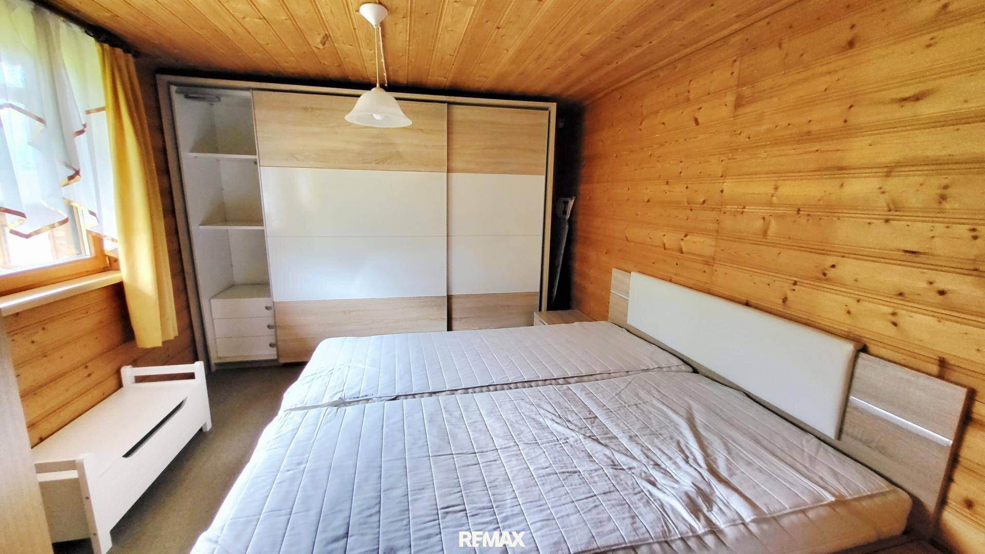 Schlafzimmer mit Holzvertäfelung, Doppelbett und großem Schiebetürenschrank.