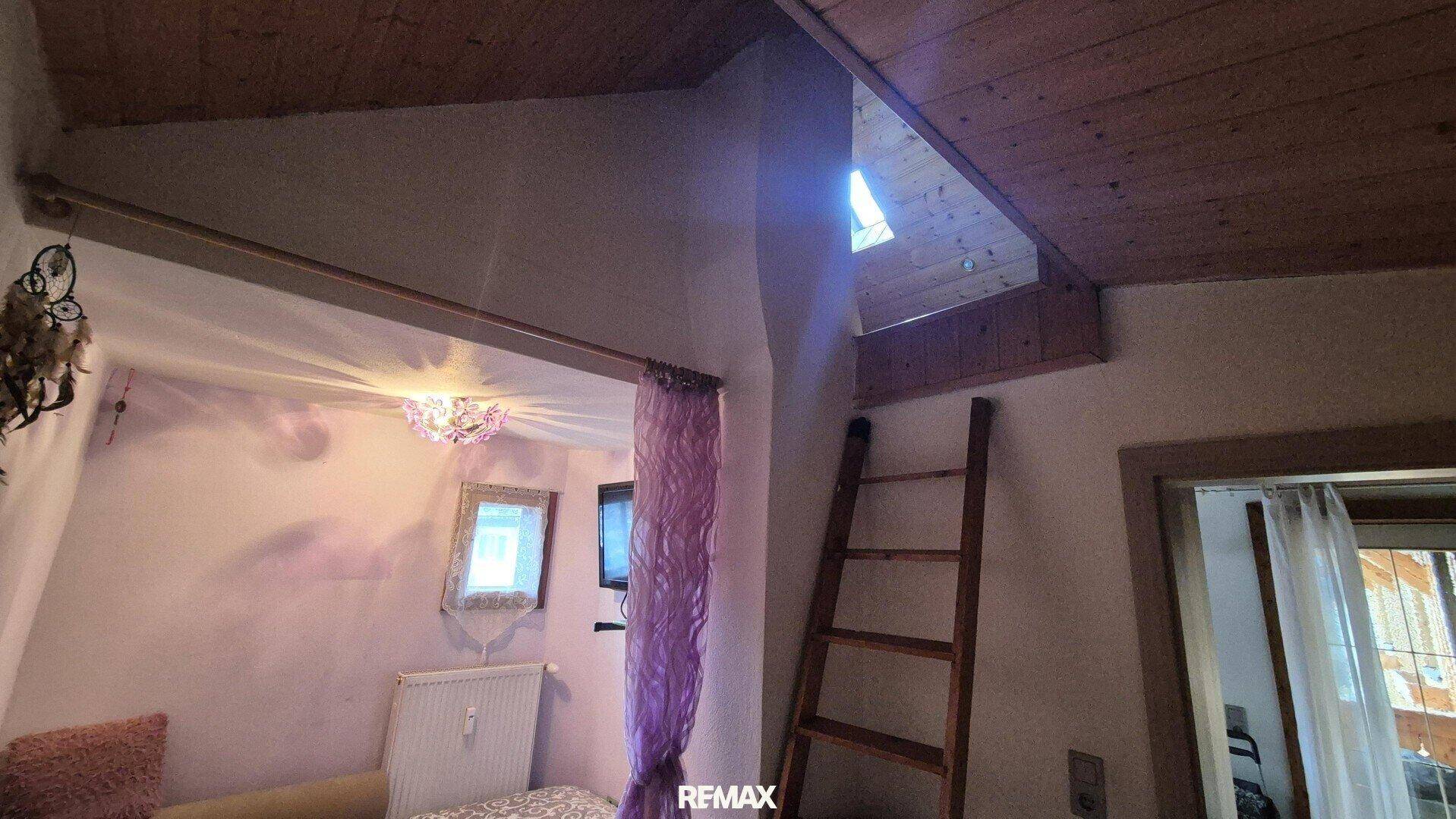 Schlafzimmer mit Zugang zu einem gemütlichen Dachbodenbereich über eine Holzleiter.