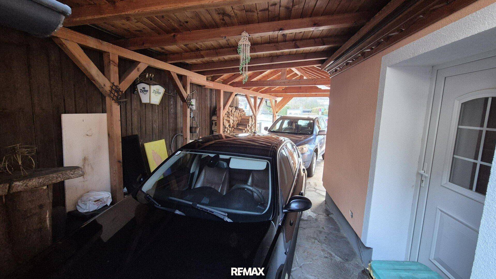 Überdachter Carport aus Holz bietet Schutz für zwei Fahrzeuge.