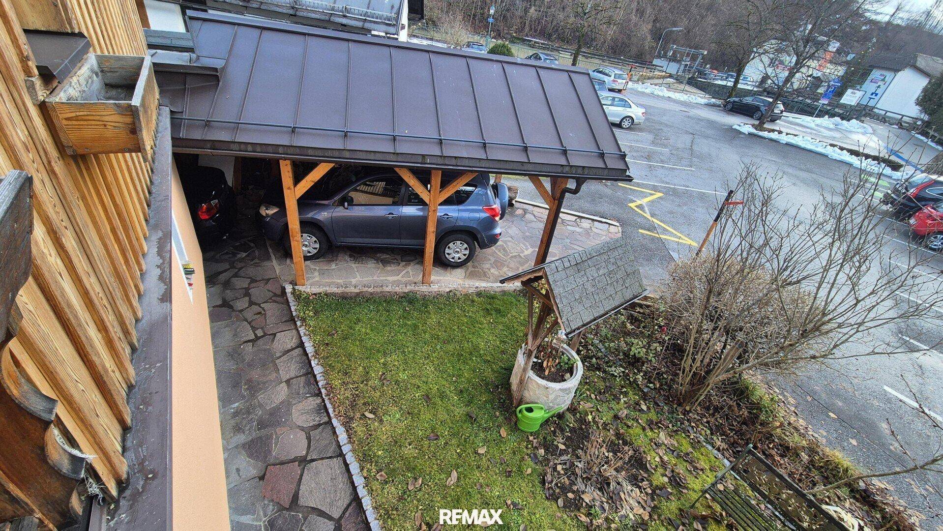 Außenansicht des Gebäudes mit Carport und angrenzendem Gartenbereich.