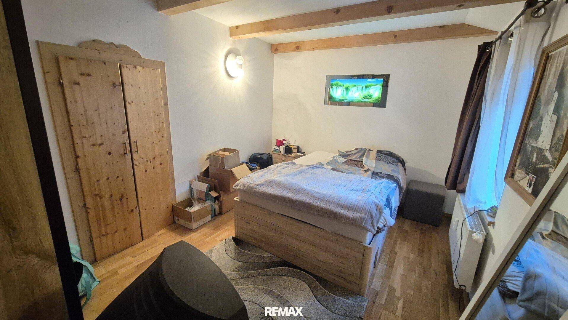 Schlafzimmer mit Holzbett, großem Holzschrank und Laminatboden.