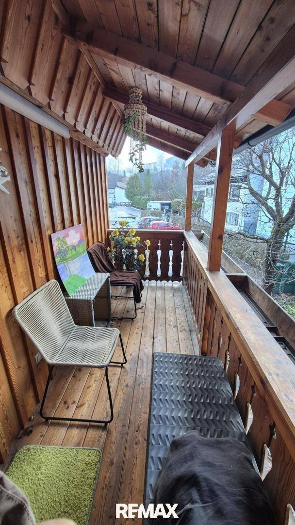 Rustikaler Holzbalkon mit Sitzmöbeln und Blick auf die umliegende Landschaft.