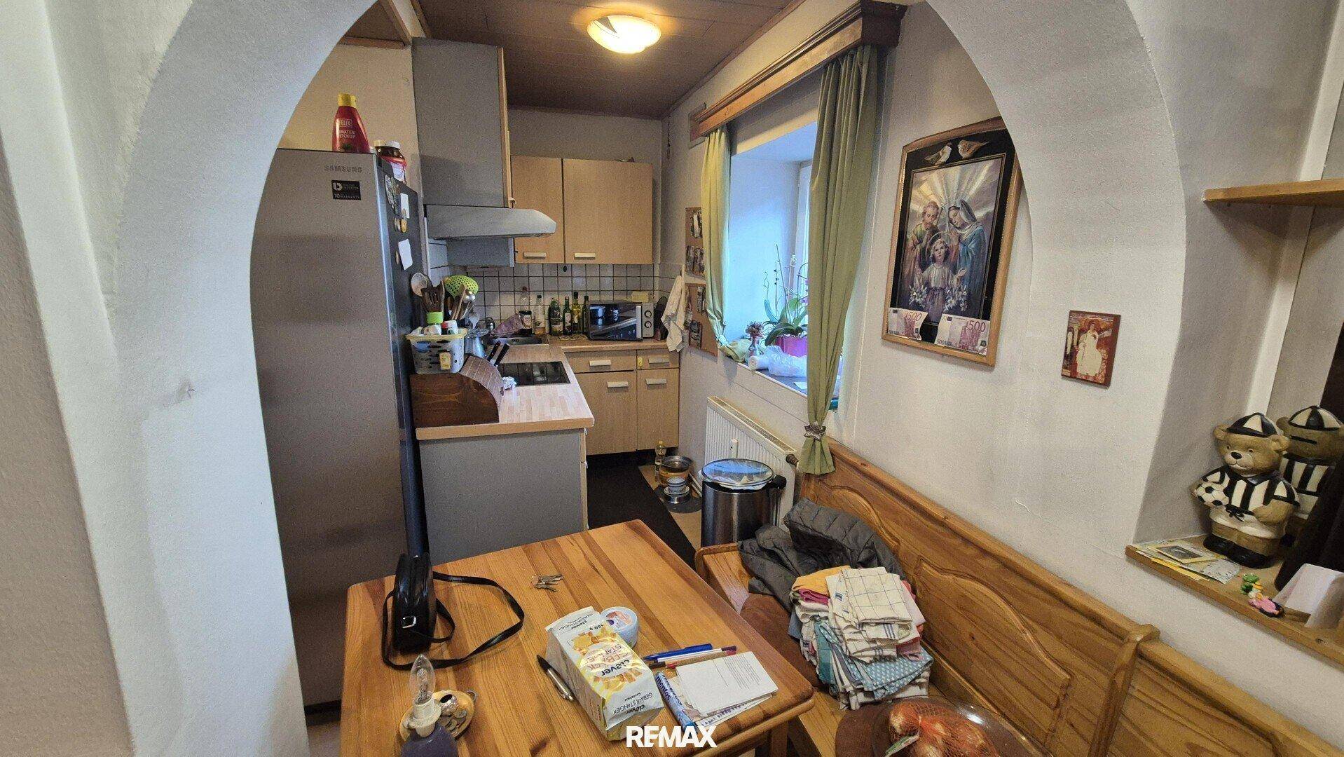 Funktionale Küche mit Holztisch, Einbauschränken und Fenster mit Blick ins Grüne.