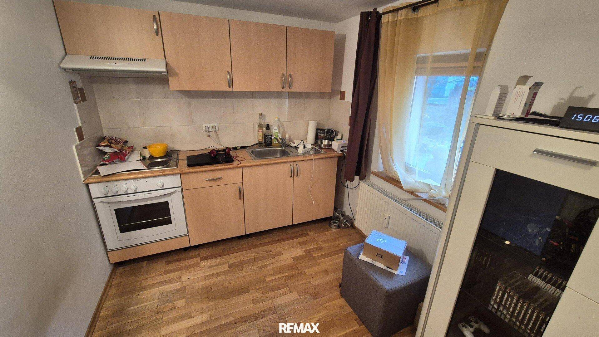Kleine Küche mit einfacher Ausstattung, Fenster und Laminatboden.