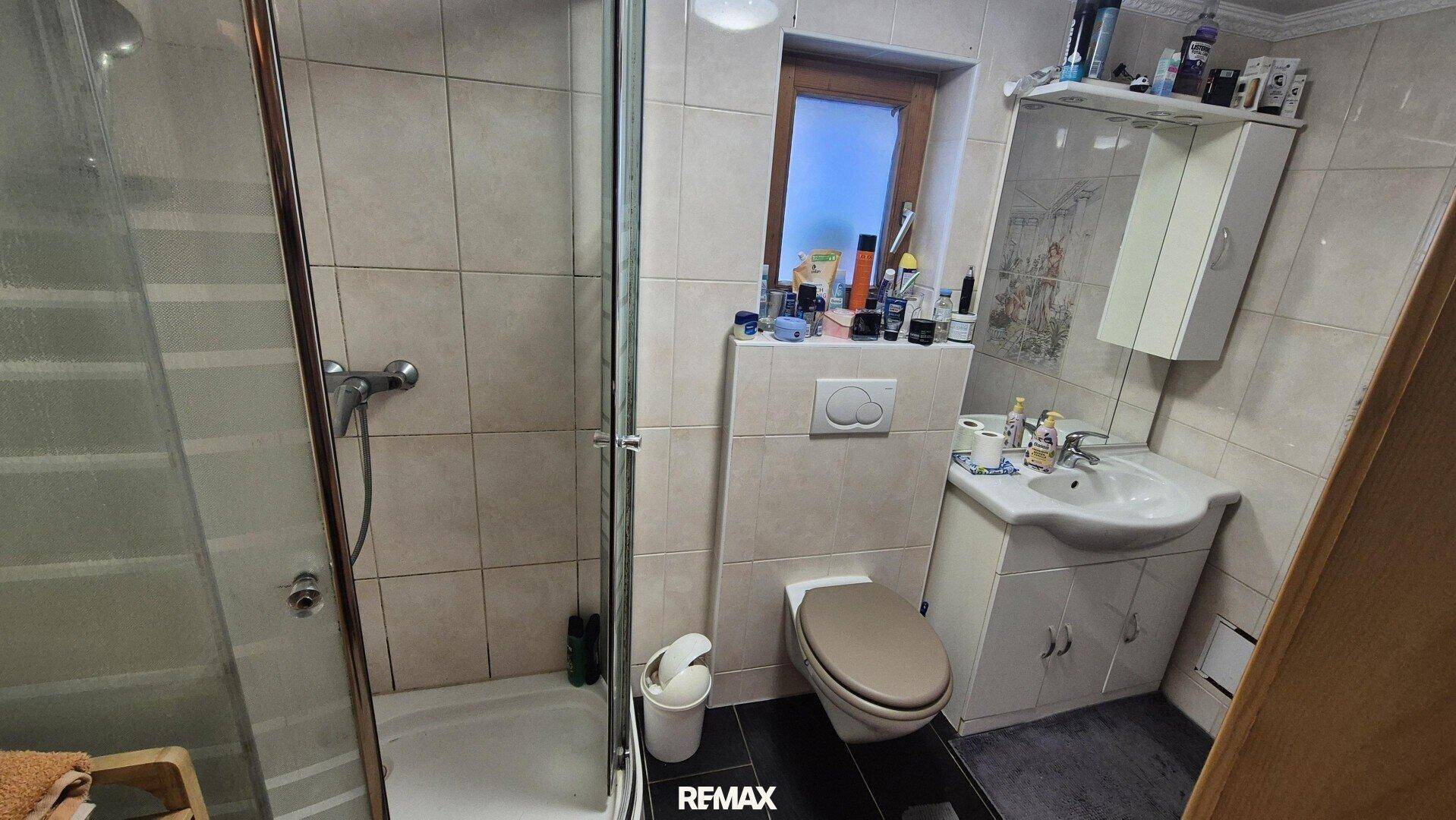 Modernisiertes Badezimmer mit Duschkabine, wandhängendem WC und Waschbecken.