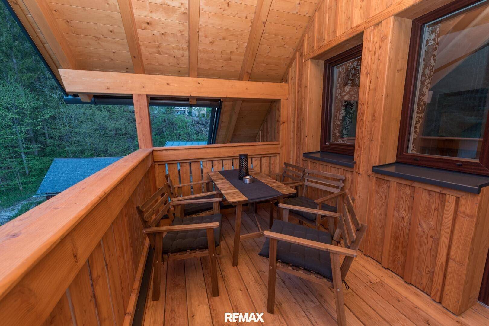 Gemütlicher Holzbalkon mit Sitzgelegenheiten und Blick ins Grüne, ideal zum Entspannen im Freien.
