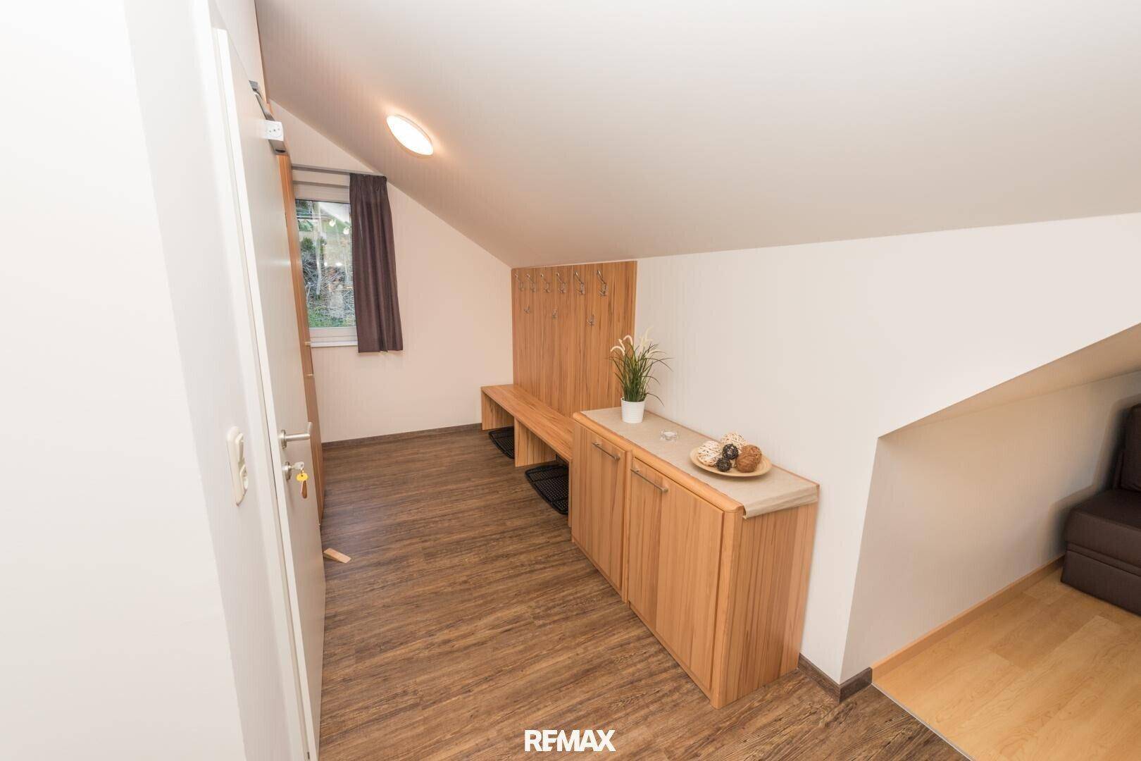 Eingangsbereich oder Flur mit Garderobe, Ablagefläche und Holzboden unter der Dachschräge.