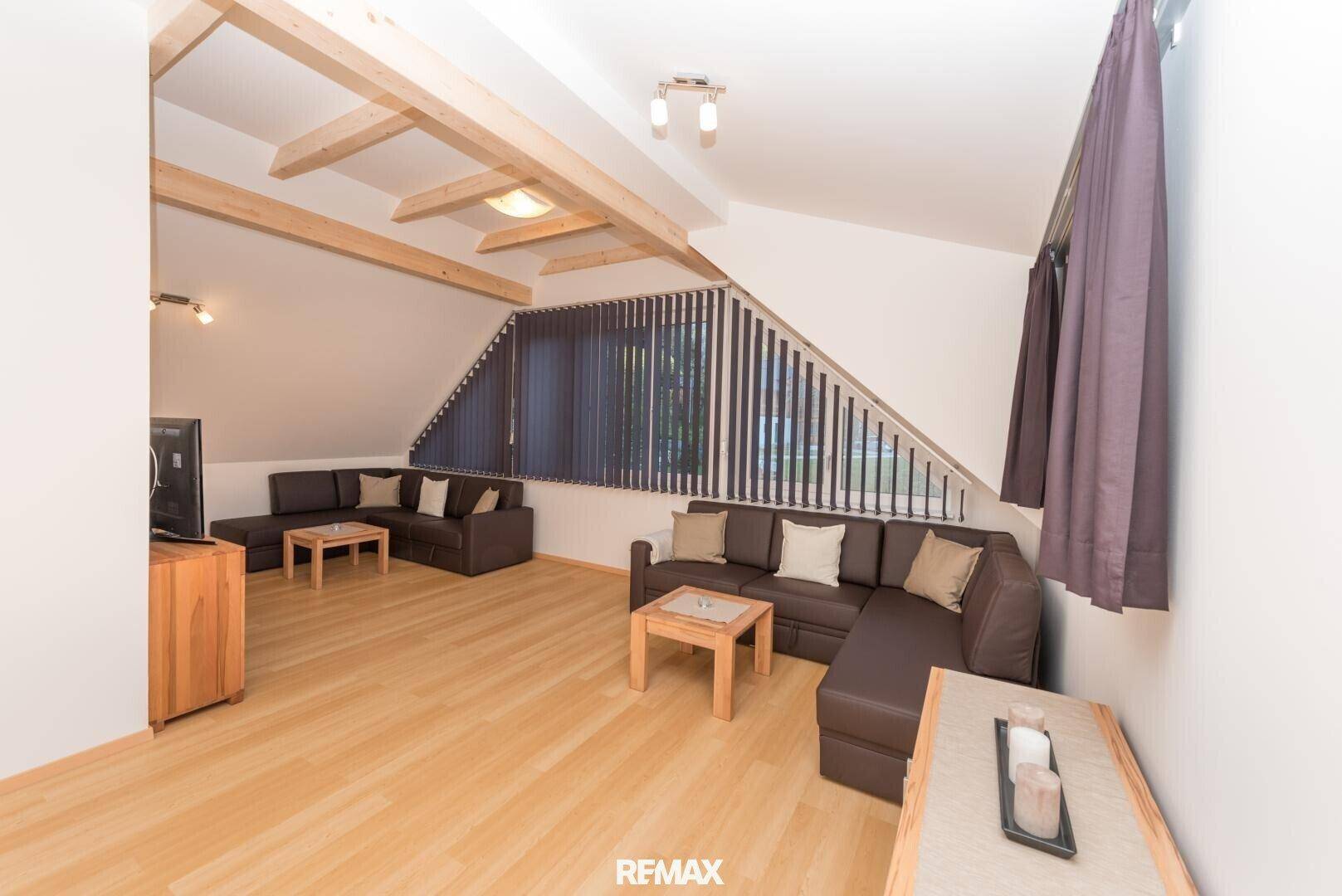 Heller Wohnbereich mit zwei Sofas, Holzboden und Dachschrägen, die Gemütlichkeit verleihen.