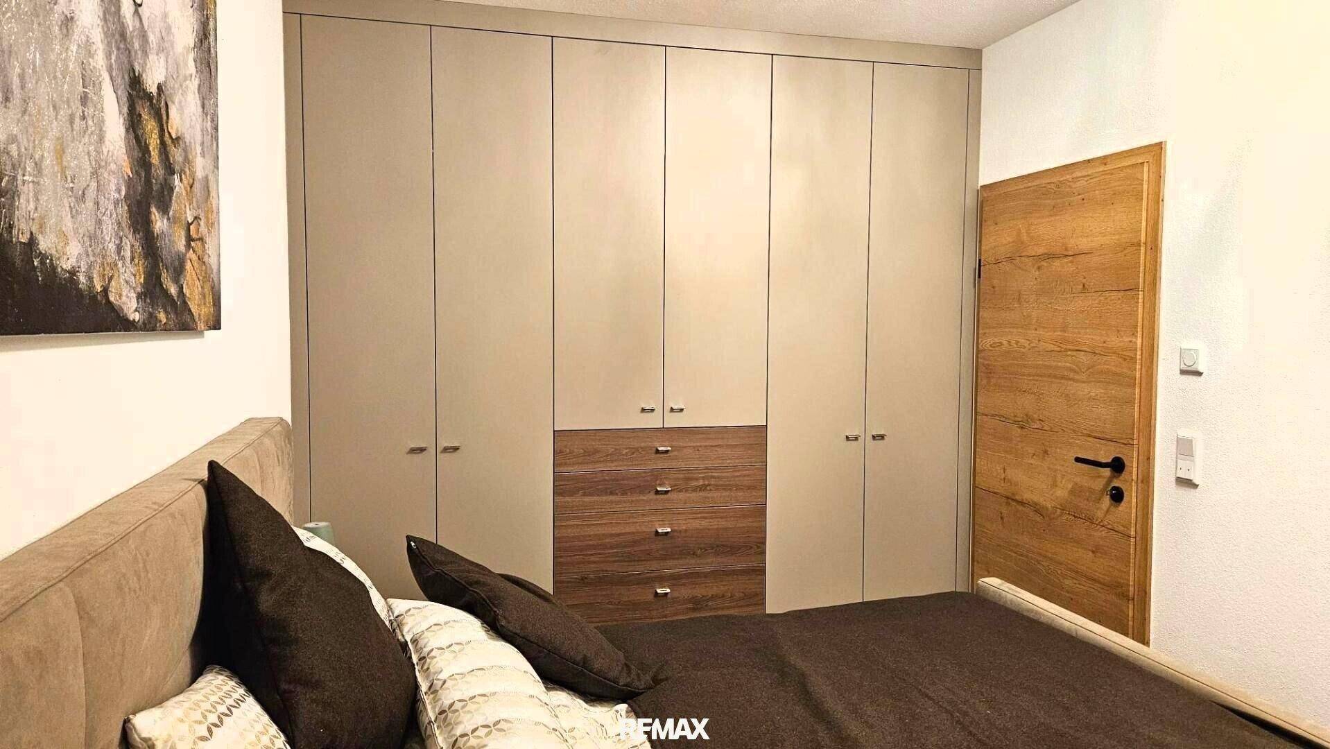 Schlafzimmer mit integrierten Kleiderschränken und Holztür, bietet viel Stauraum und modernes Design.