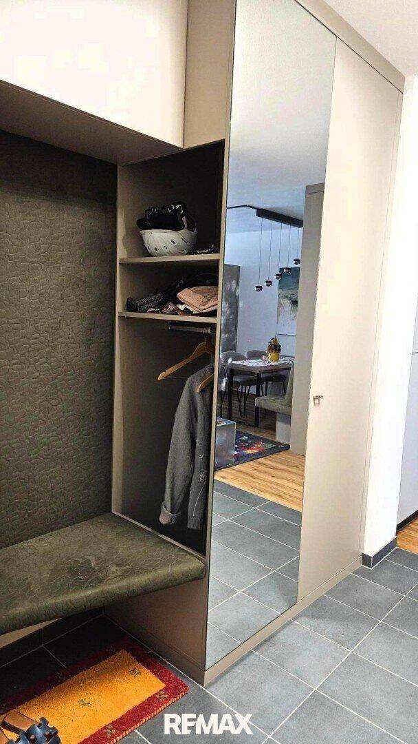 Heller Eingangsbereich mit integrierter Sitzbank, Ablagen und großem Spiegelschrank, funktional und stilvoll.