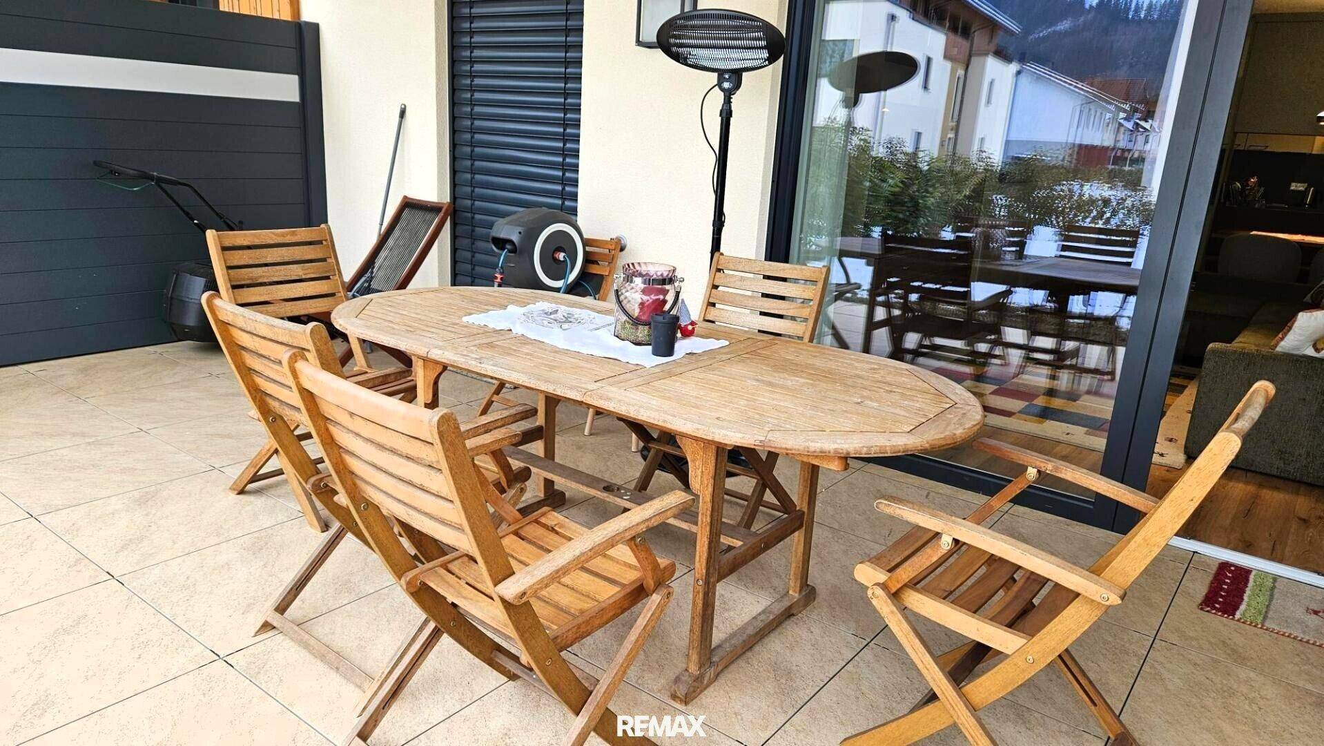 Gemütliche Terrasse mit rustikalen Holzmöbeln und Heizstrahler für kühle Abende im Freien.