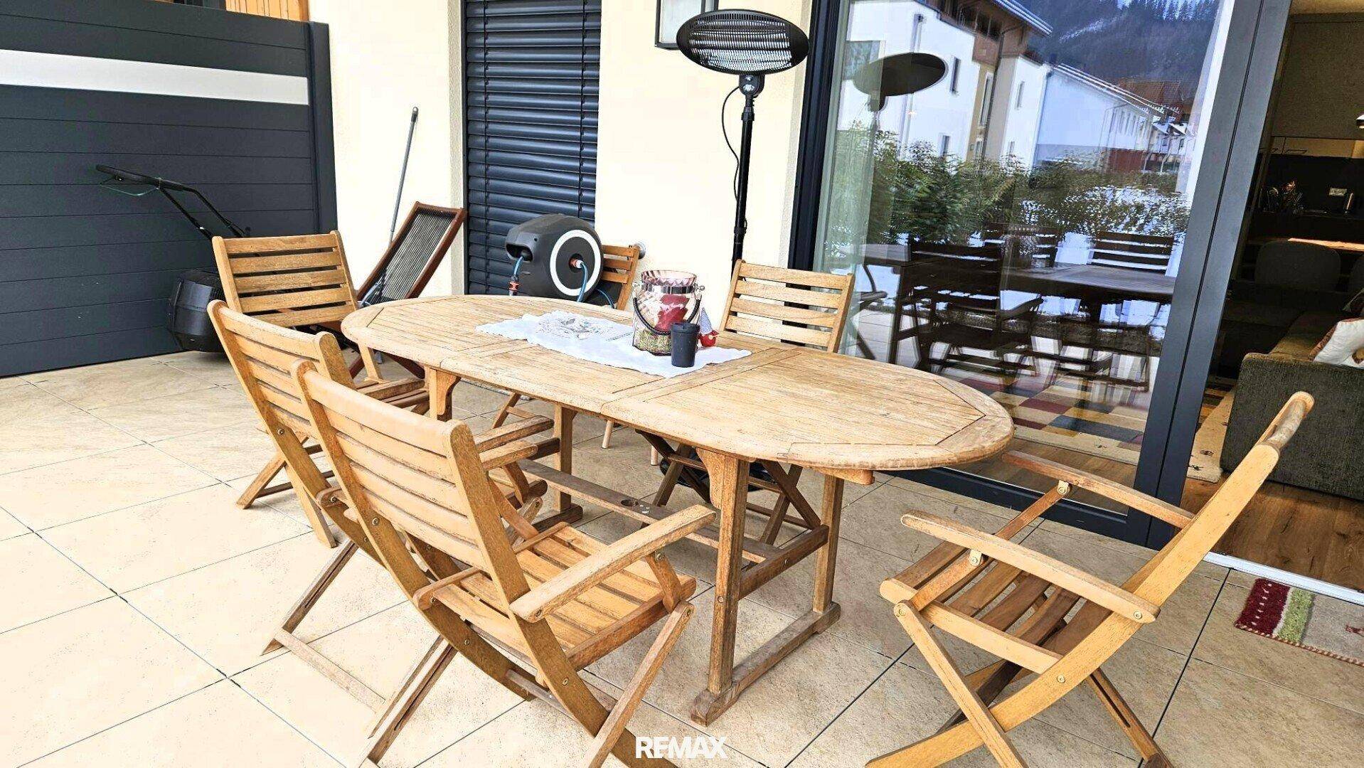 Gemütliche Terrasse mit rustikalen Holzmöbeln und Heizstrahler für kühle Abende im Freien.