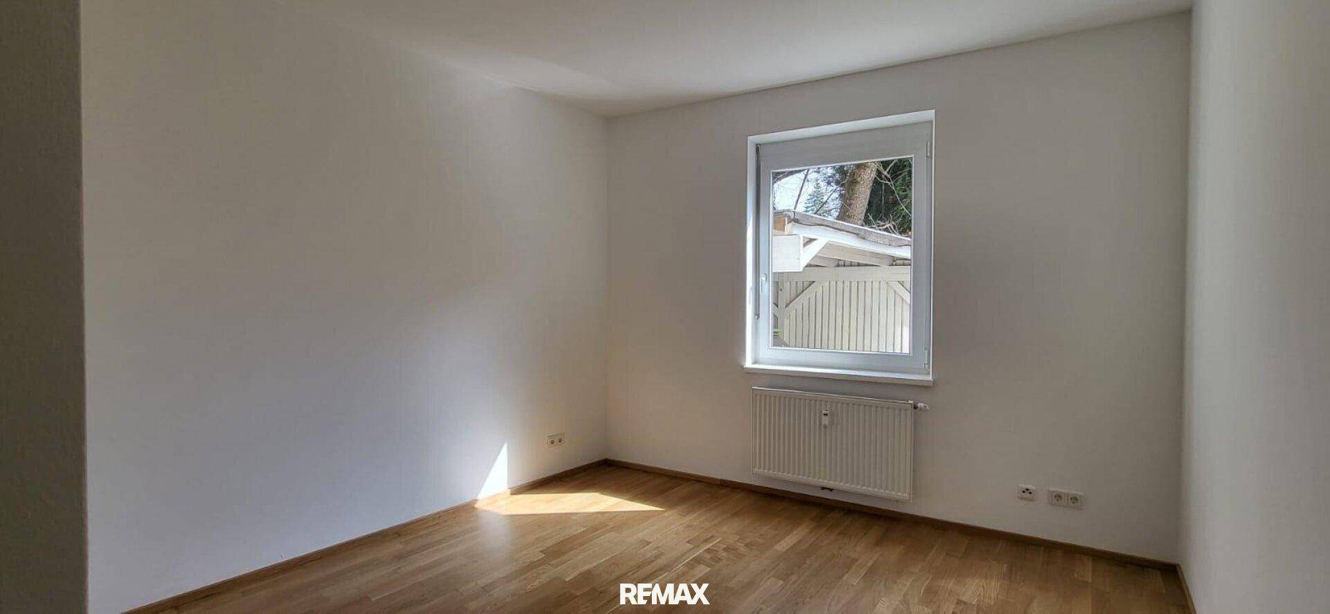 Helles Zimmer mit Holzboden, weißen Wänden und viel Sonnenlicht, das durch das Fenster fällt.