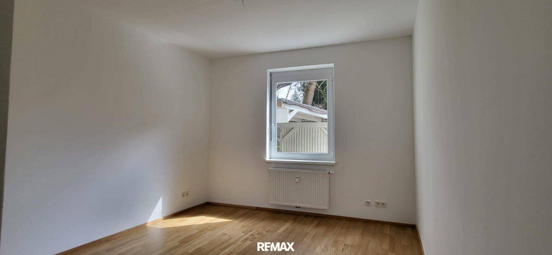 Helles Zimmer mit Holzboden, weißen Wänden und einem Fenster, das viel Tageslicht hereinlässt.