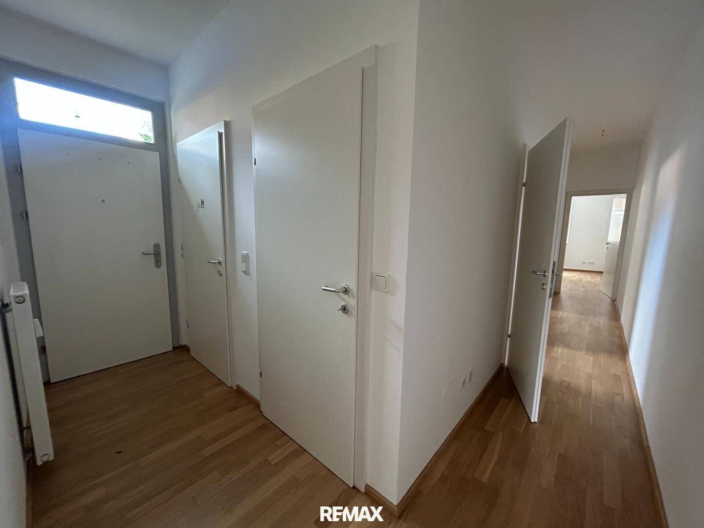 Heller Flur mit Holzboden und mehreren weißen Türen, die zu verschiedenen Räumen führen.