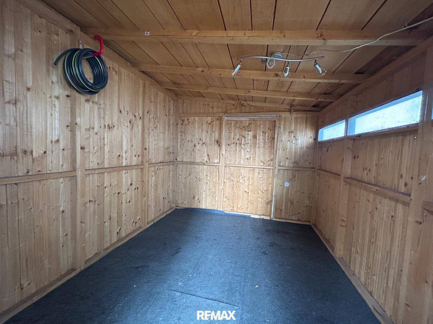 Innenansicht eines Holzschuppens mit Holzwänden und -decke, ideal als Werkstatt.