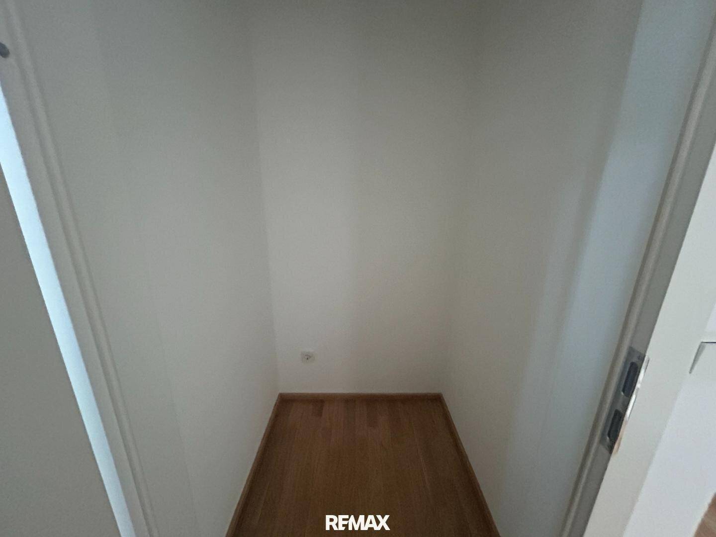 Leerer Abstellraum mit Holzboden und weißen Wänden, bereit zur Nutzung.