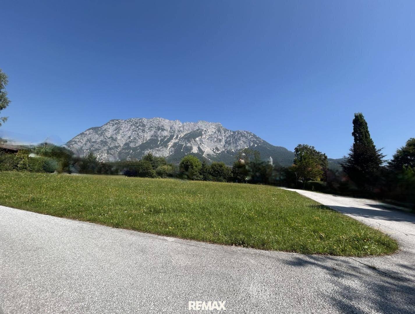 Idyllische grüne Landschaft mit majestätischem Bergpanorama im Hintergrund an einem sonnigen Tag.