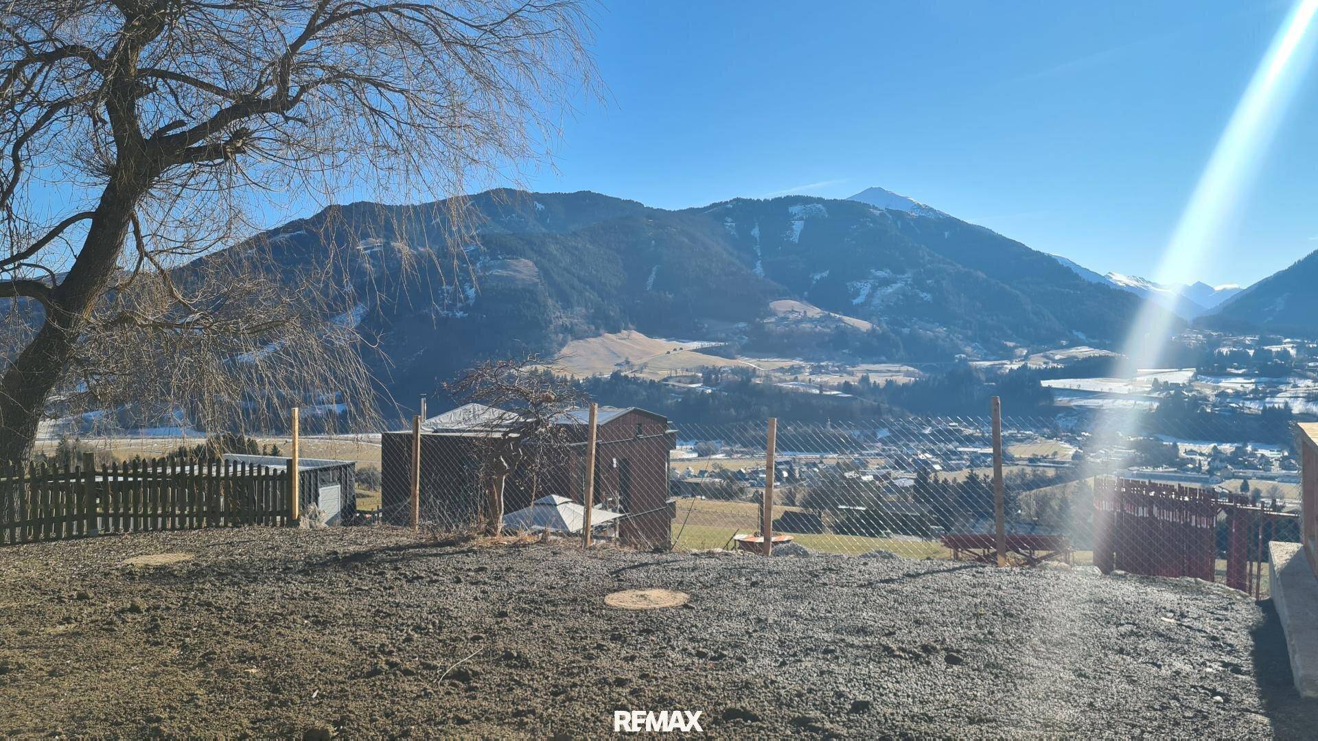 Grundstück mit weitem Bergblick und vorbereiteter Gartenfläche unter strahlend blauem Himmel.