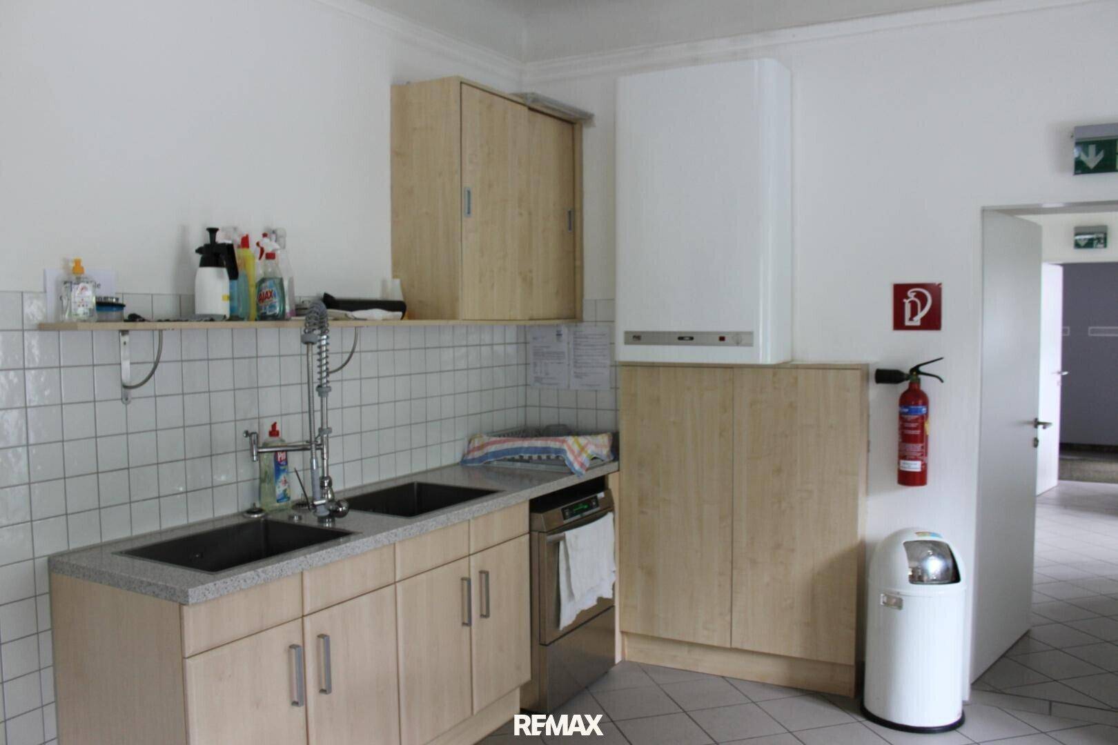 Praktische Spülküche mit Doppelwaschbecken, Fliesenwand und einem Warmwasserbereiter an der Wand.