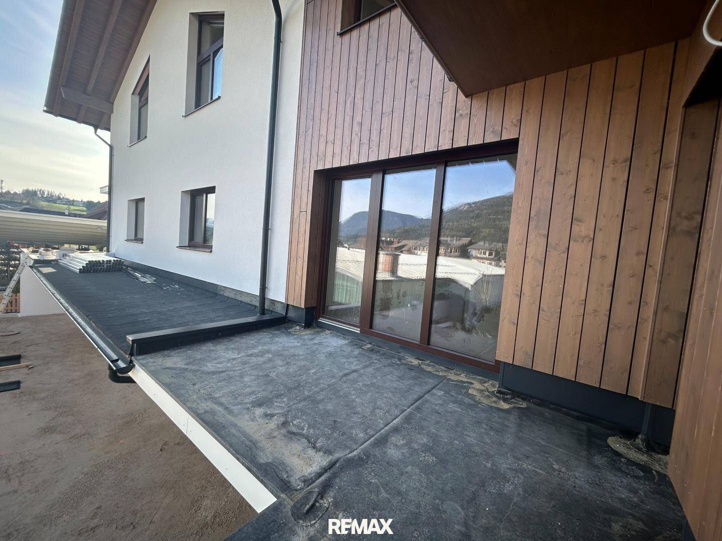 Unfertige Terrasse mit Zugang zum Gebäude, bereit für die Endgestaltung.